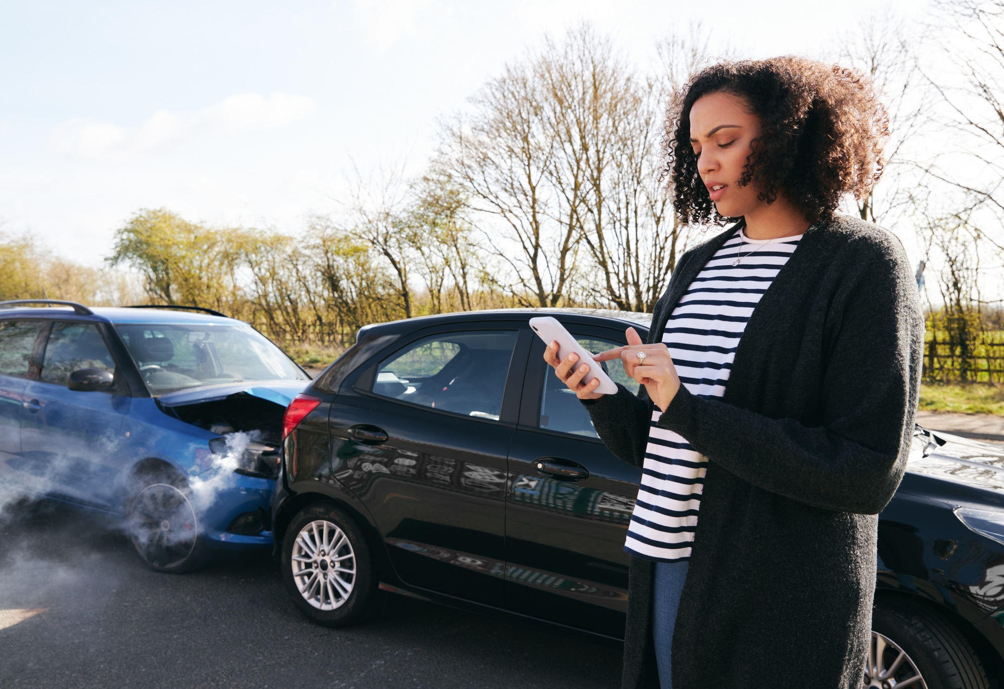 Female Driver Contacting Car Insurance Company On Mobile Phone After Road Traffic Accident